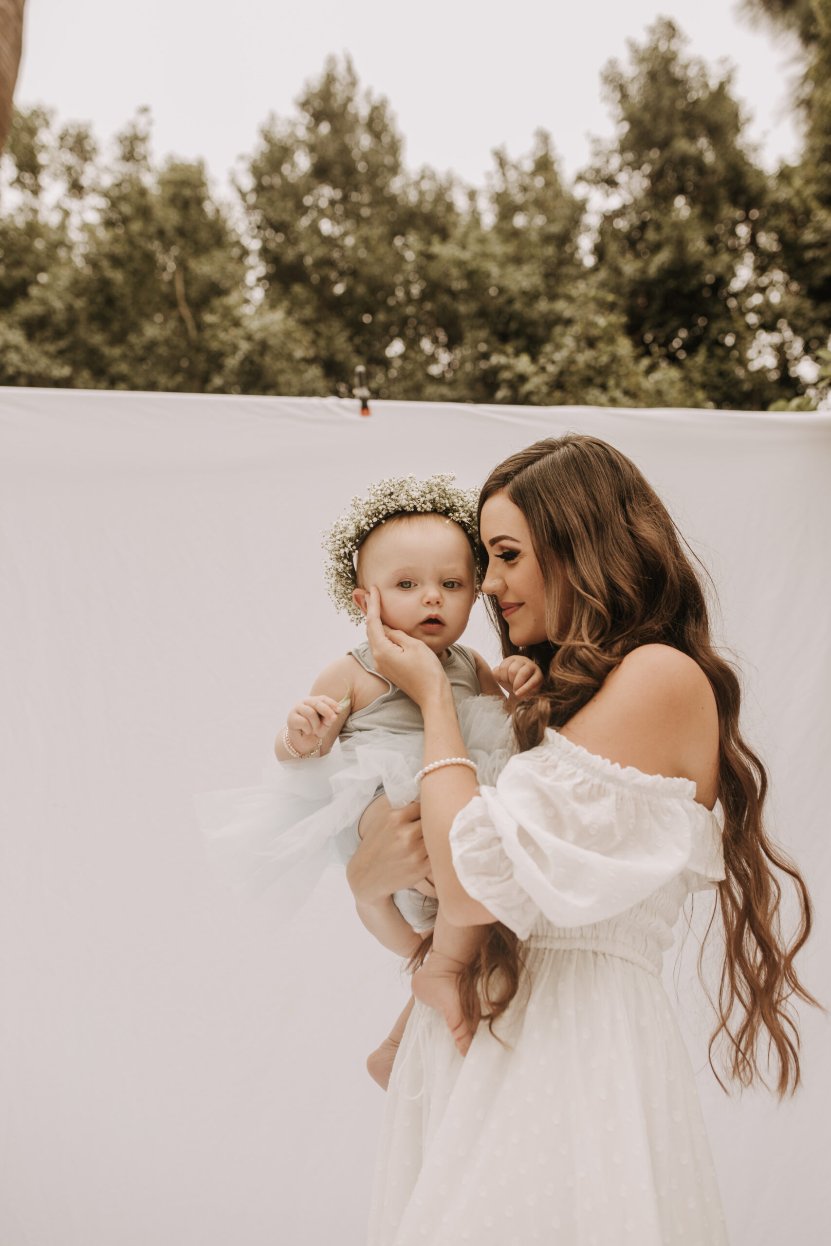 springtime soft light daisies mama and me mom and baby white dress white backdrop flower crown motherhood photos motherhood photography San Diego maternity photographer family photographer Sabrina kinsella outdoor photos green trees backyard mini session