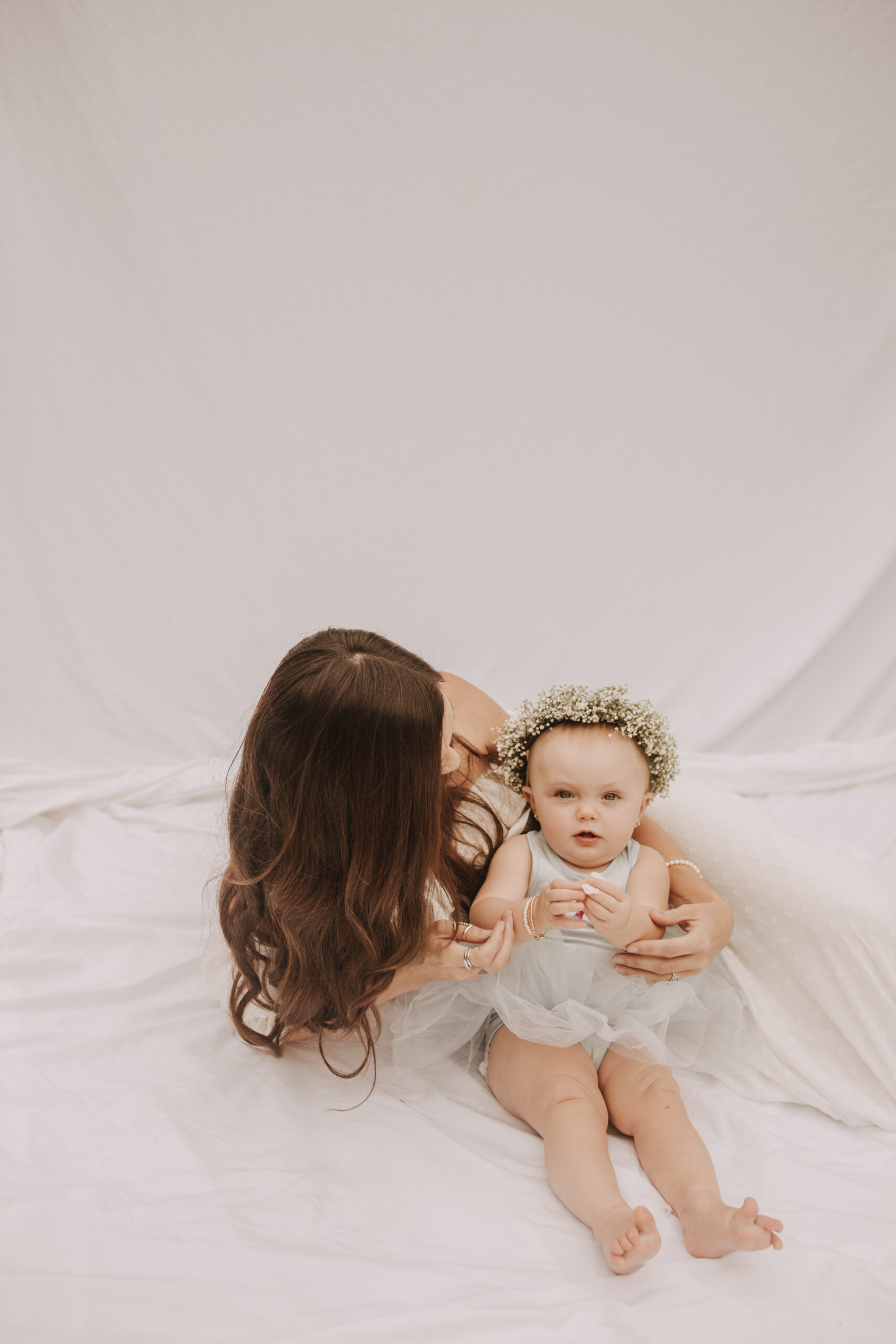 springtime soft light daisies mama and me mom and baby white dress white backdrop flower crown motherhood photos motherhood photography San Diego maternity photographer family photographer Sabrina kinsella outdoor photos green trees backyard mini session