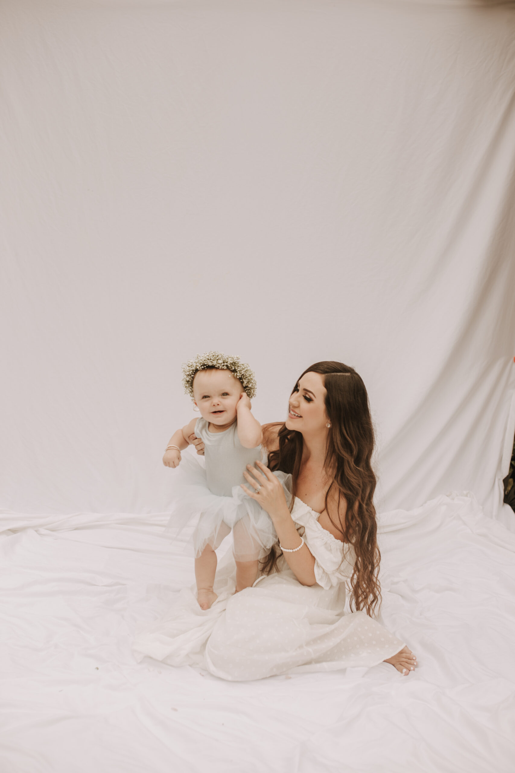 springtime soft light daisies mama and me mom and baby white dress white backdrop flower crown motherhood photos motherhood photography San Diego maternity photographer family photographer Sabrina kinsella outdoor photos green trees backyard mini session