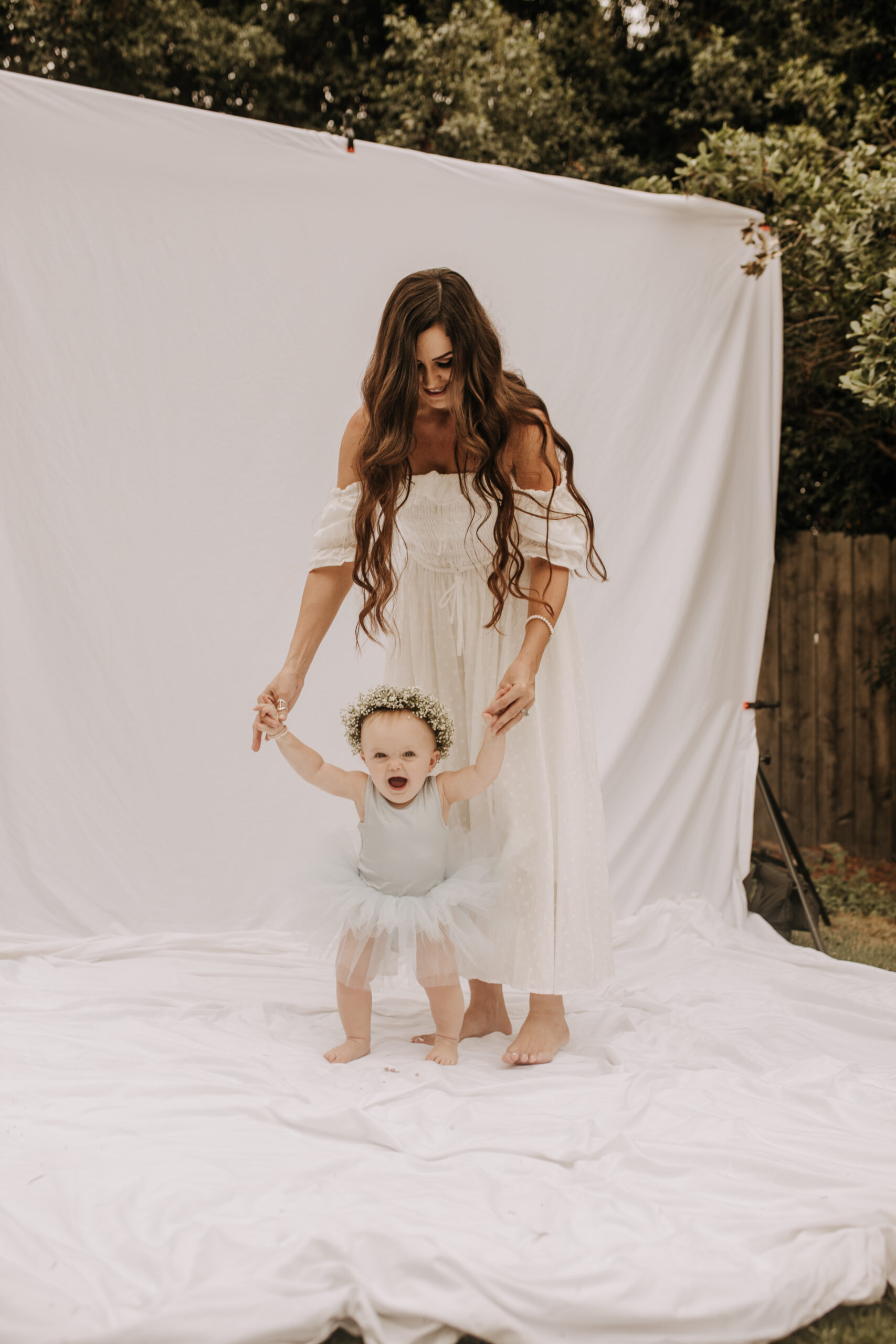 springtime soft light daisies mama and me mom and baby white dress white backdrop flower crown motherhood photos motherhood photography San Diego maternity photographer family photographer Sabrina kinsella outdoor photos green trees backyard mini session