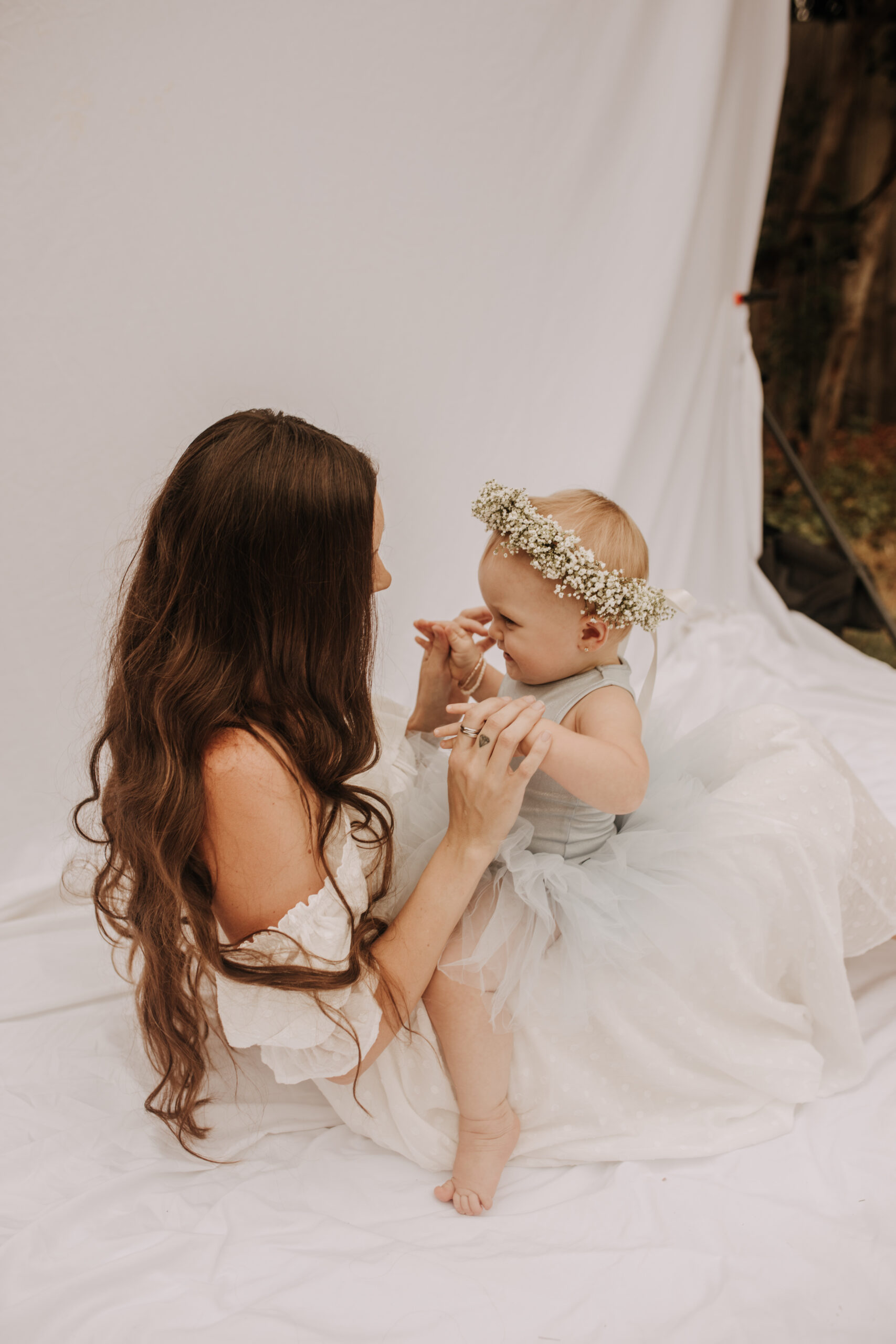 springtime soft light daisies mama and me mom and baby white dress white backdrop flower crown motherhood photos motherhood photography San Diego maternity photographer family photographer Sabrina kinsella outdoor photos green trees backyard mini session