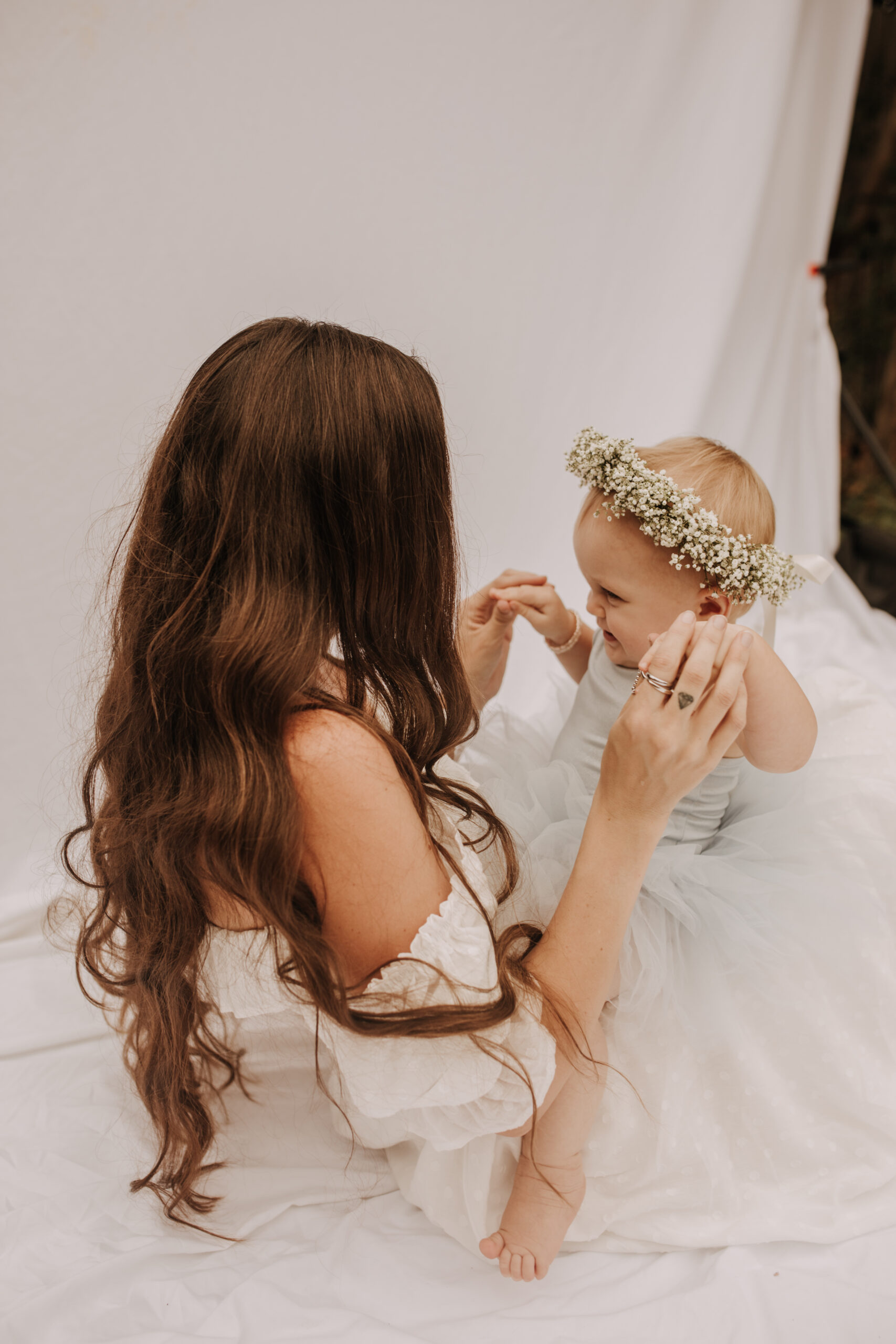 springtime soft light daisies mama and me mom and baby white dress white backdrop flower crown motherhood photos motherhood photography San Diego maternity photographer family photographer Sabrina kinsella outdoor photos green trees backyard mini session