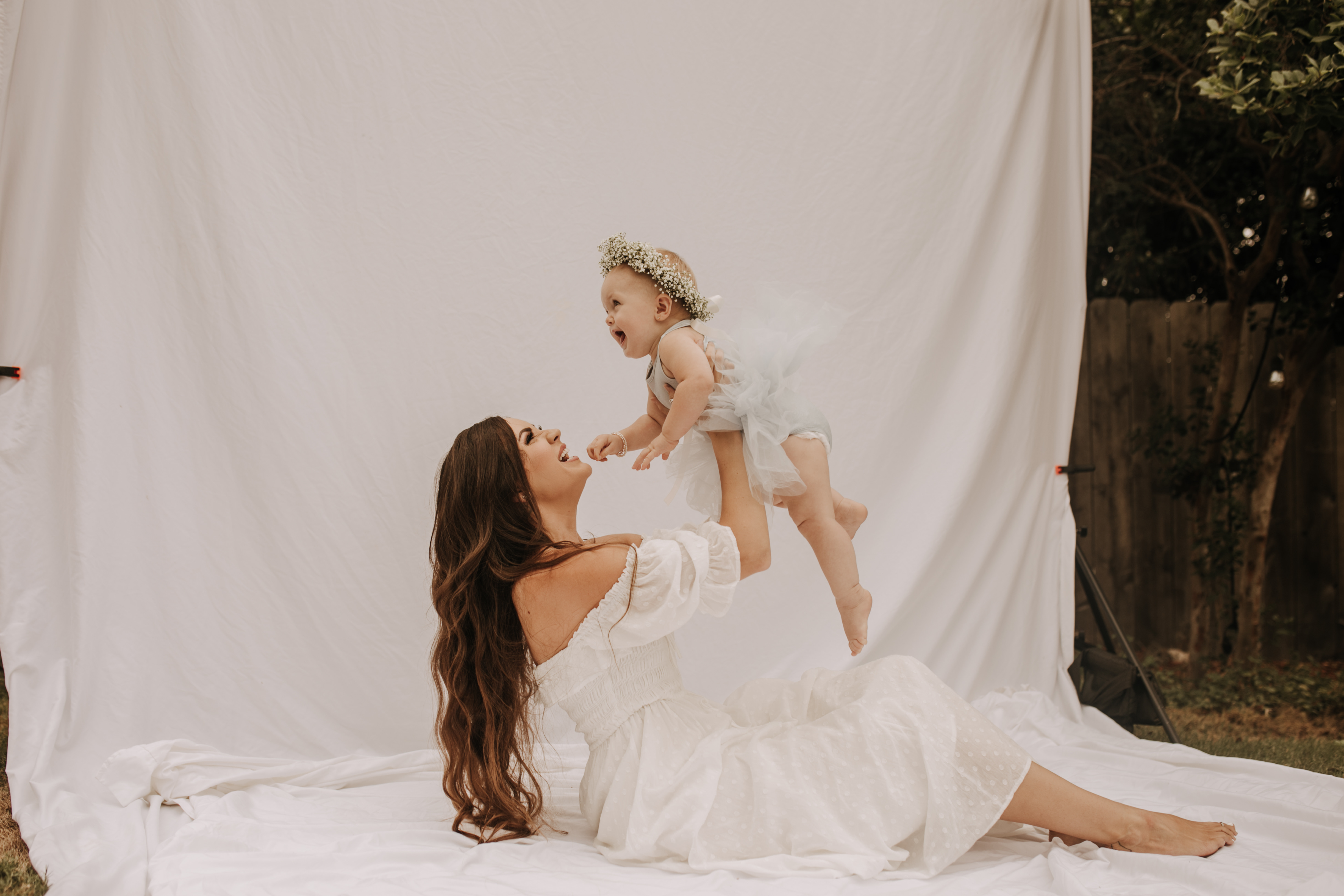 springtime soft light daisies mama and me mom and baby white dress white backdrop flower crown motherhood photos motherhood photography San Diego maternity photographer family photographer Sabrina kinsella outdoor photos green trees backyard mini session