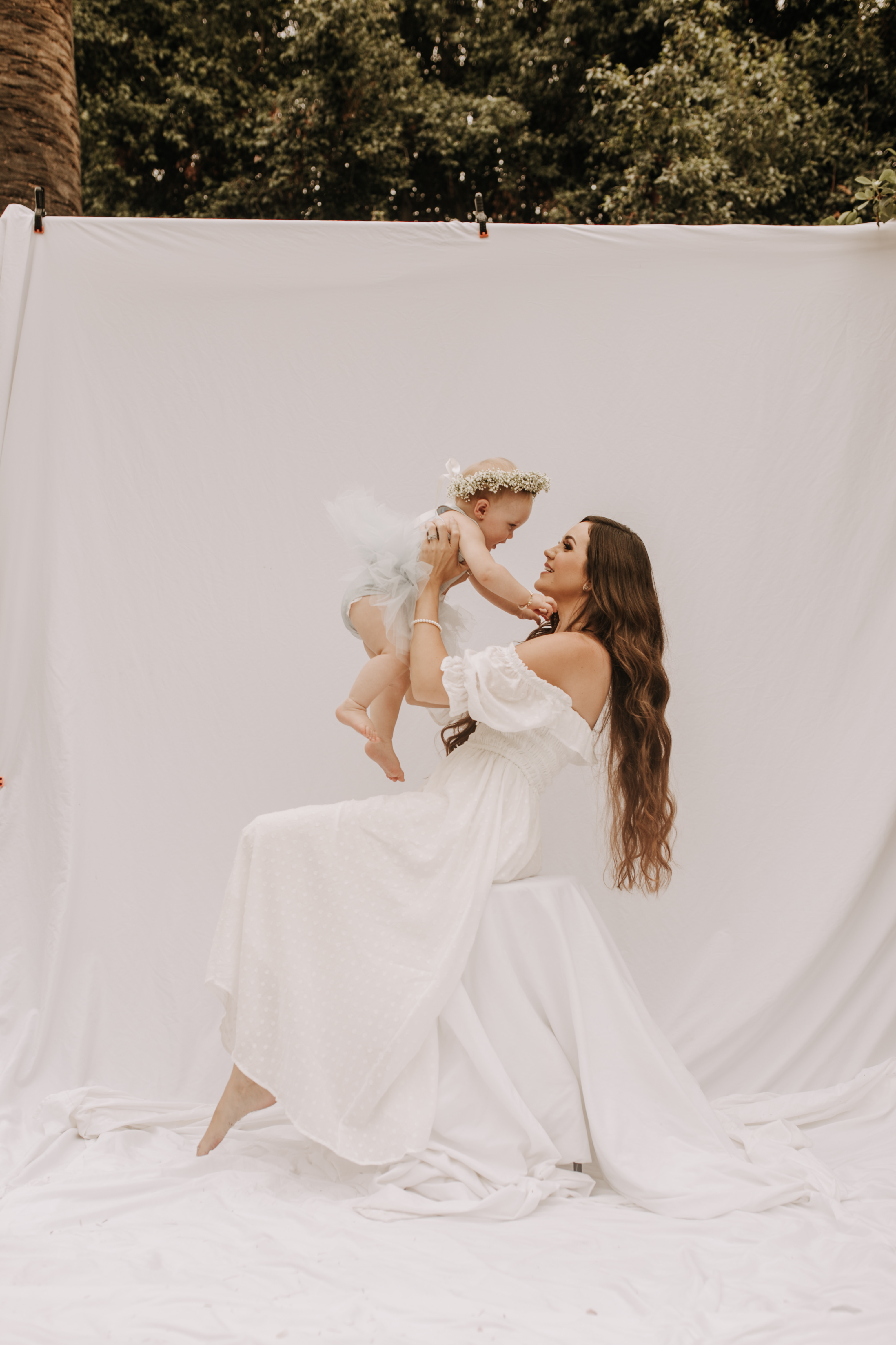 springtime soft light daisies mama and me mom and baby white dress white backdrop flower crown motherhood photos motherhood photography San Diego maternity photographer family photographer Sabrina kinsella outdoor photos green trees backyard mini session