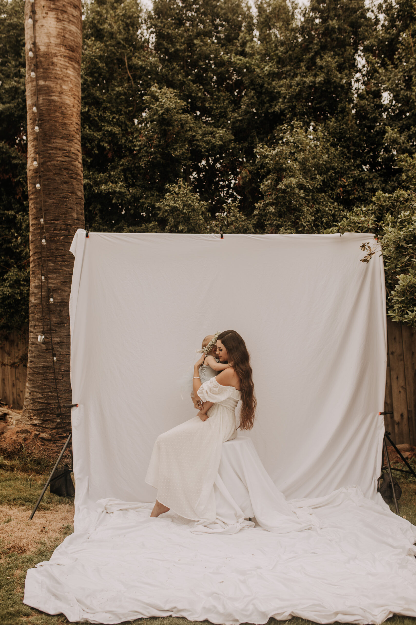 springtime soft light daisies mama and me mom and baby white dress white backdrop flower crown motherhood photos motherhood photography San Diego maternity photographer family photographer Sabrina kinsella outdoor photos green trees backyard mini session