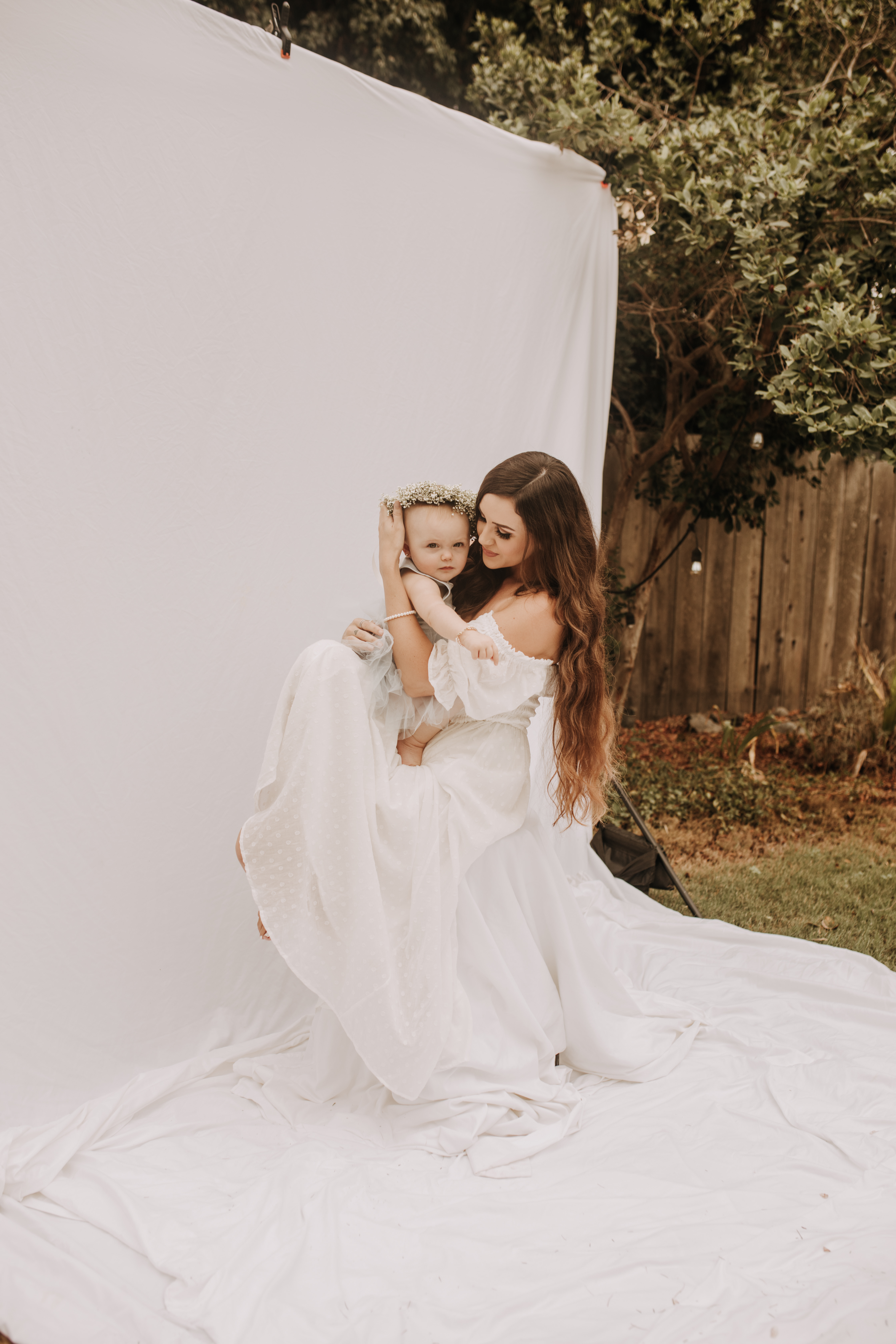 springtime soft light daisies mama and me mom and baby white dress white backdrop flower crown motherhood photos motherhood photography San Diego maternity photographer family photographer Sabrina kinsella outdoor photos green trees backyard mini session