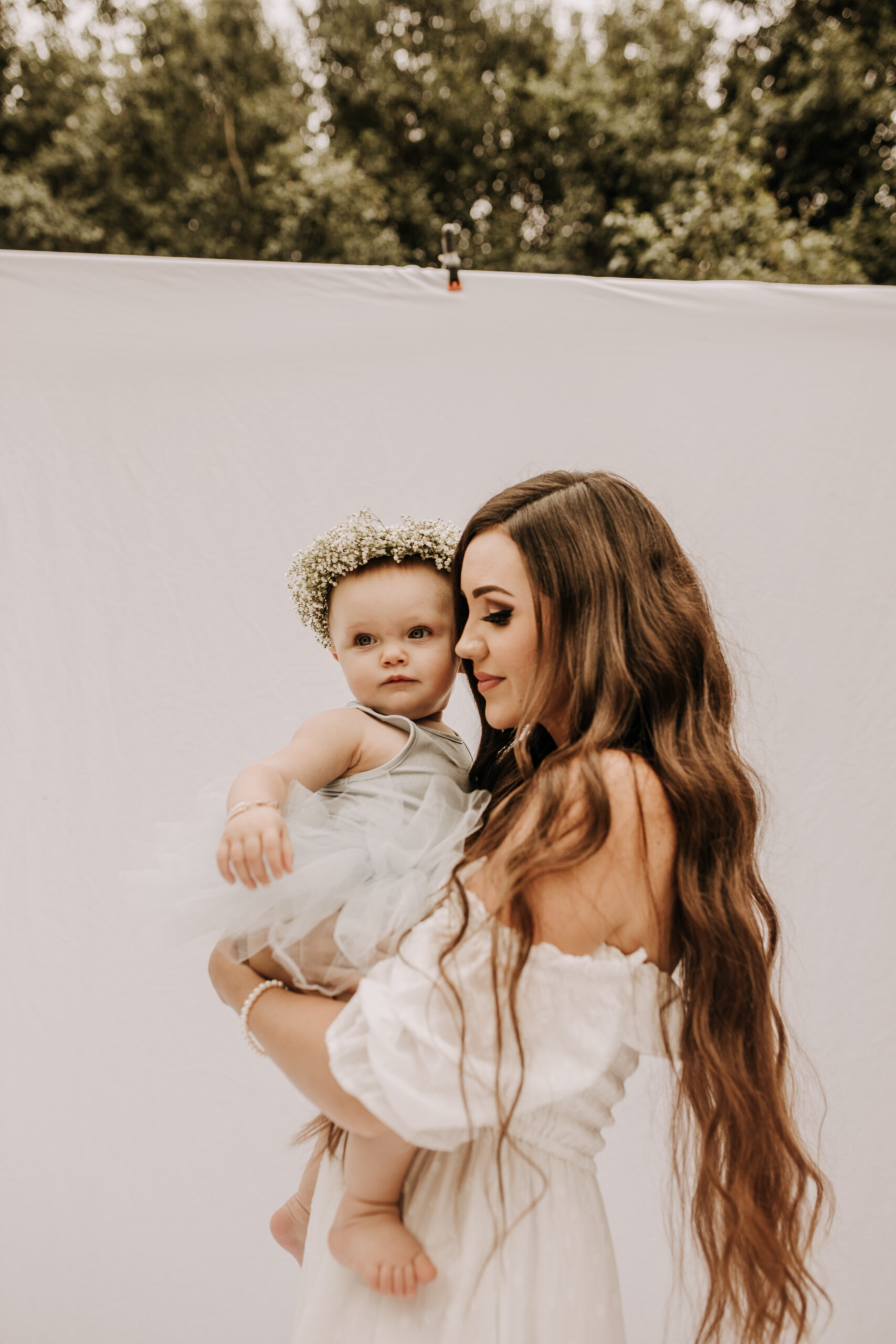 springtime soft light daisies mama and me mom and baby white dress white backdrop flower crown motherhood photos motherhood photography San Diego maternity photographer family photographer Sabrina kinsella outdoor photos green trees backyard mini session