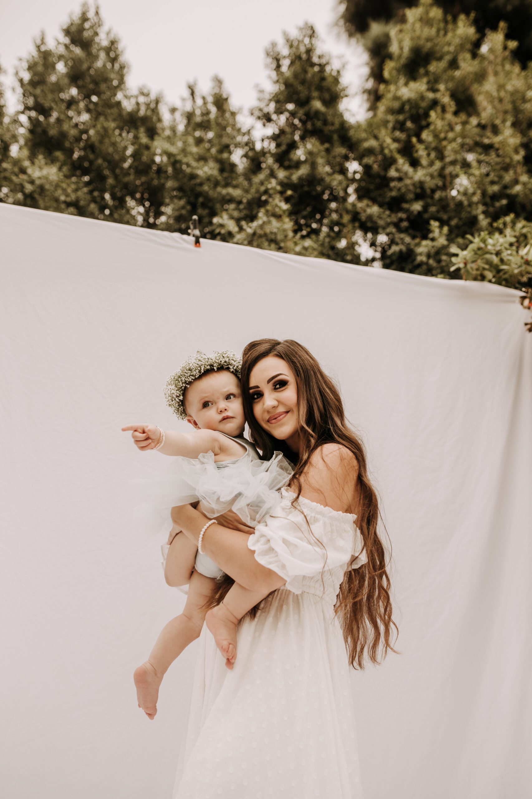 springtime soft light daisies mama and me mom and baby white dress white backdrop flower crown motherhood photos motherhood photography San Diego maternity photographer family photographer Sabrina kinsella outdoor photos green trees backyard mini session