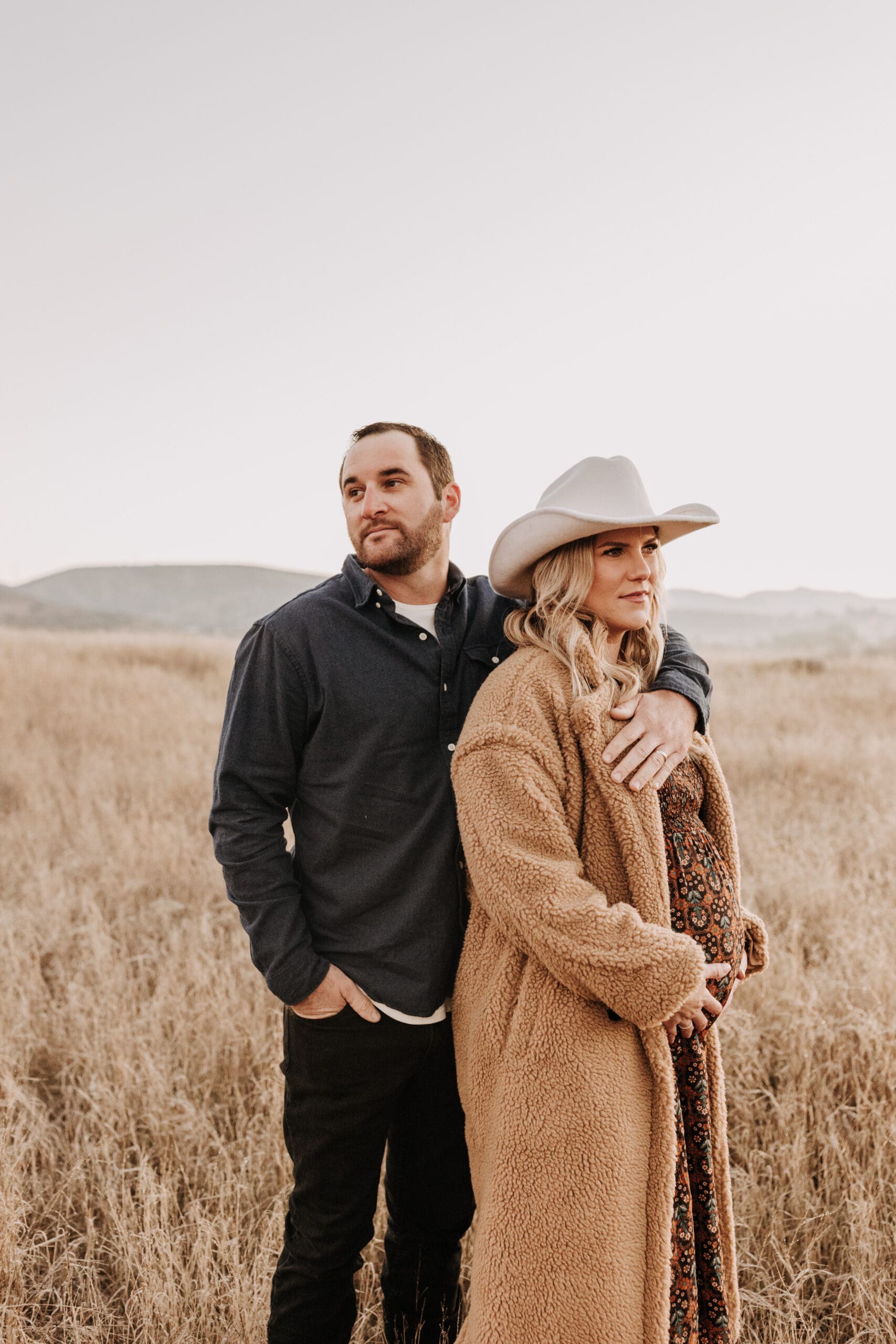 outdoor warm western maternity cowboy hat field brown tones maternity dress fall maternity pregnancy Yellowstone themed shoot outdoor sunrise maternity San Diego family photographer Sabrina kinsella sabrinalynnphoto