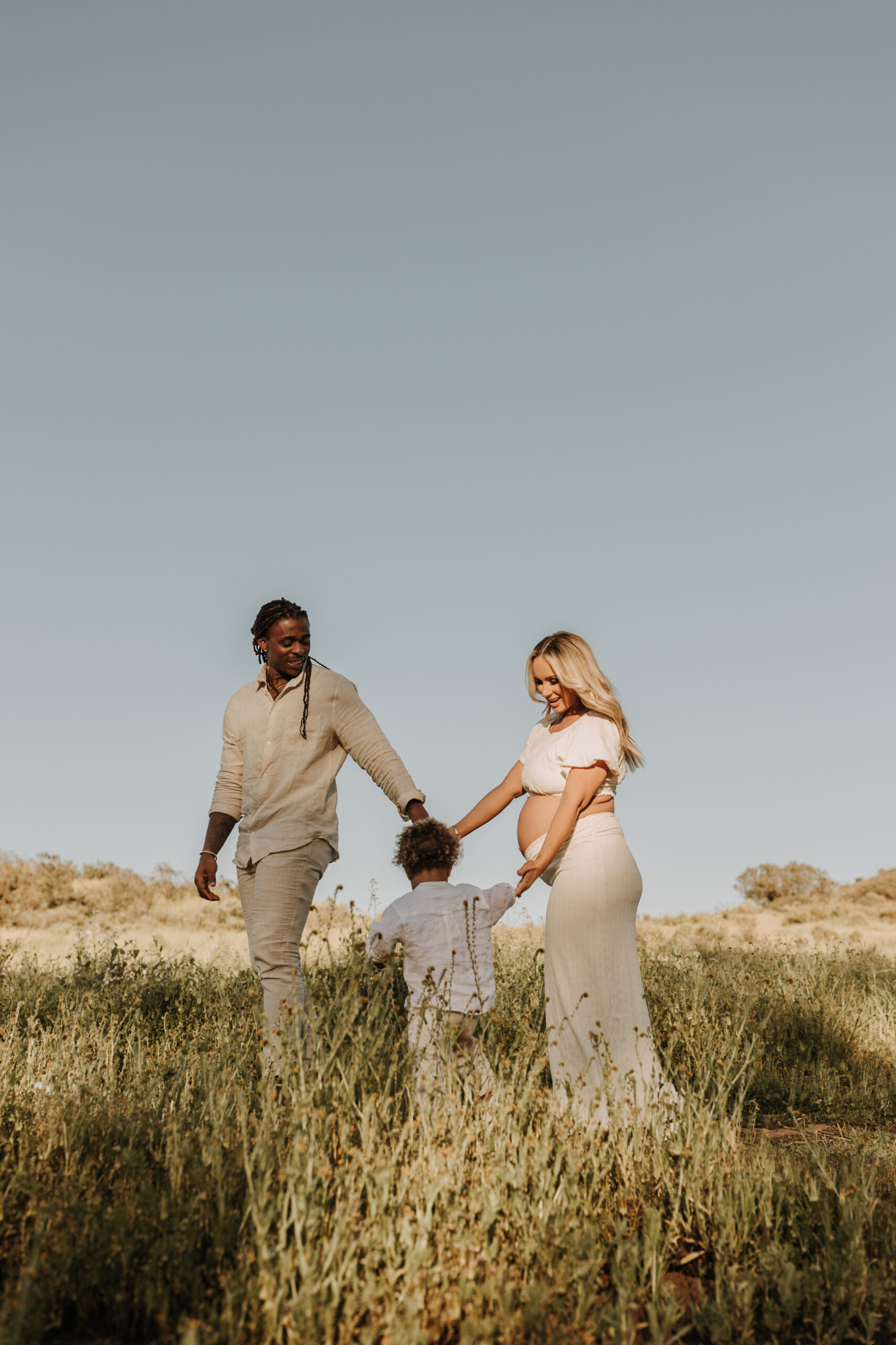 outdoor candid family photos springtime floral maternity photos family of three outdoor in a field San Diego family photographer Sabrina kinsella sabrinalynnphoto