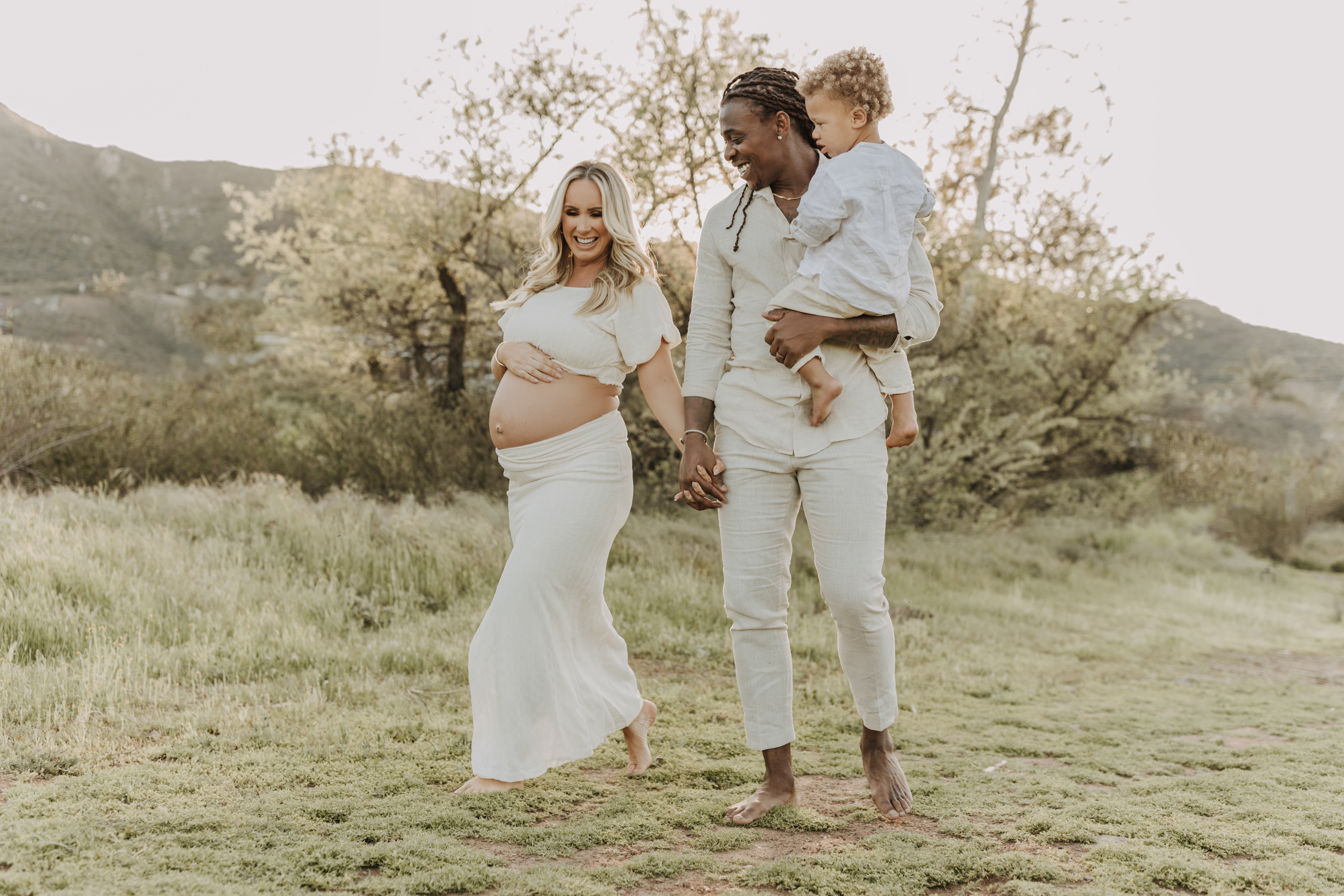 outdoor candid family photos springtime floral maternity photos family of three outdoor in a field San Diego family photographer Sabrina kinsella sabrinalynnphoto