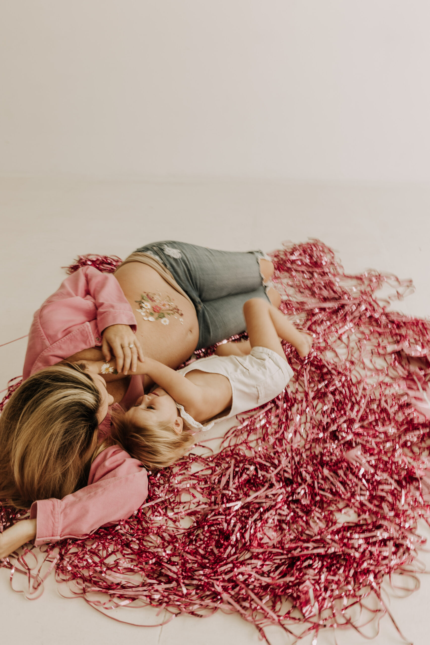 studio photography session pink maternity photos in a studio white backdrop pink confetti streamers mama and me motherhood mini sessions family photos candid maternity photos styled shoot San Diego maternity photographer Sabrinalynnphoto Sabrina kinsella