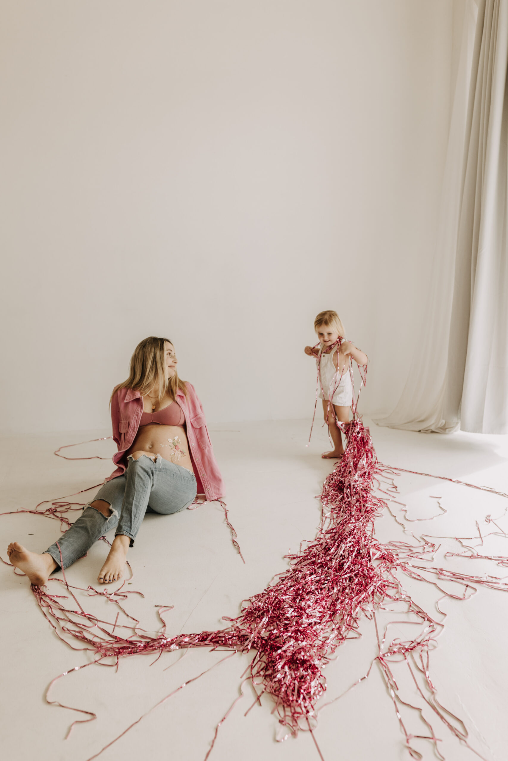 studio photography session pink maternity photos in a studio white backdrop pink confetti streamers mama and me motherhood mini sessions family photos candid maternity photos styled shoot San Diego maternity photographer Sabrinalynnphoto Sabrina kinsella